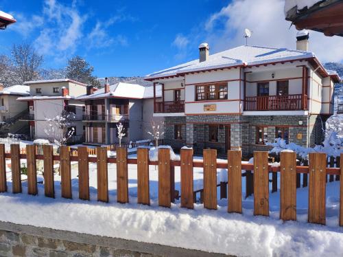 a house with a fence in the snow at NUCA GUESTHOUSE in Metsovo