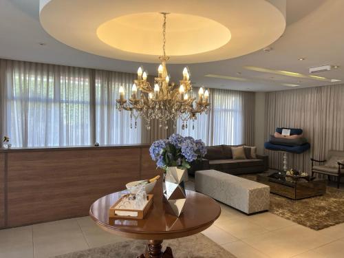 a living room with a table and a chandelier at Flats Chateau Campos do Jordão in Campos do Jordão