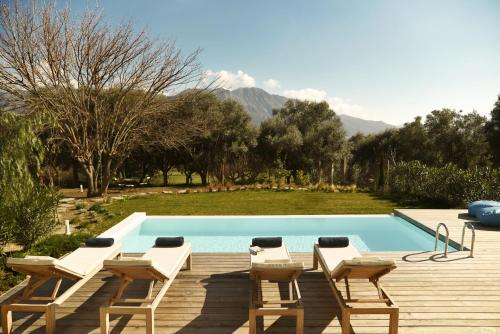 a pool with chairs and a deck with a view of the mountains at Villa Mouria private villa just 200m from the sea in Pogoniá