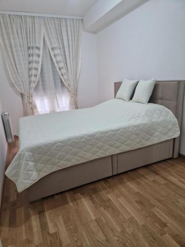 łóżko w białym pokoju z oknem w obiekcie The Apartment w mieście Skopje