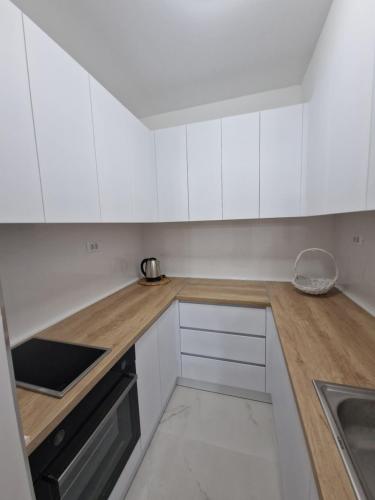 kuchnia z białymi szafkami i drewnianym blatem w obiekcie The Apartment w mieście Skopje