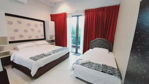 a bedroom with two beds and a window with red curtains at Bulan Guesthouse Imago in Kota Kinabalu