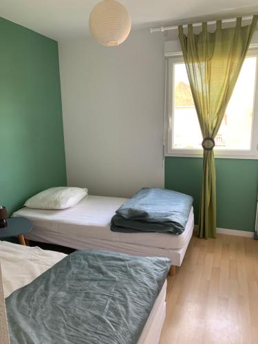 two beds in a room with a window at L'appartement du parc vert marine in Houlgate