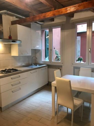 a kitchen with white cabinets and a table and chairs at Casa Gioia Centro Storico in Bologna