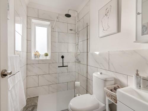 a white bathroom with a toilet and a shower at Heritage Cottage in Flamborough