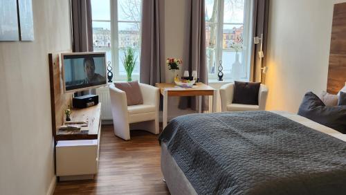 Habitación de hotel con cama, TV y mesa. en Das Ferienapartment Alexandrine direkt am Pfaffenteich mit eigenem Parkplatz en Schwerin