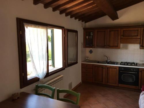 une cuisine avec des placards en bois, une fenêtre et une table dans l'établissement La Ramaccia: relax a Montescudaio, à Montescudaio