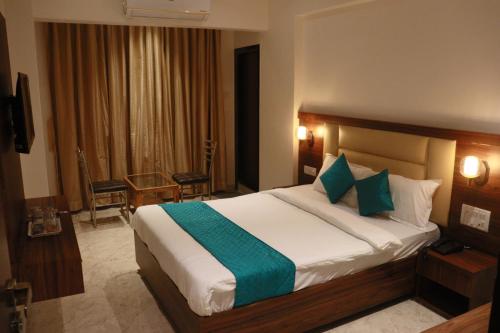a bedroom with a large bed with green and white pillows at Hotel Candor Amigo Airoli Mind Space in Navi Mumbai
