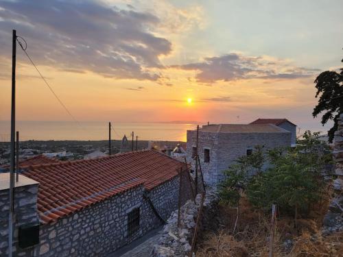 a sunset over a brick building with the sun in the sky at Filia's House (The House of Friendship) in Areopolis