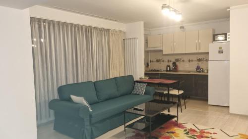 a living room with a blue couch and a kitchen at Tibiscum Apartament, Bucuresti in Bucharest
