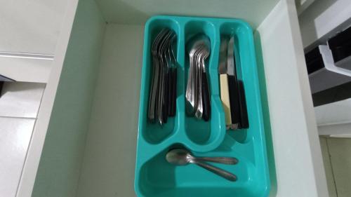 a green tray with utensils in a drawer at Apartamento Resort Palmeiras 2 com 03 Quartos Ubatuba in Ubatuba