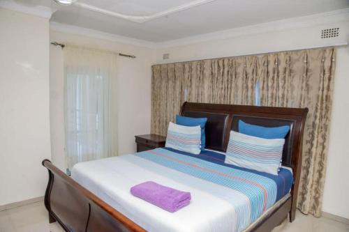 a bedroom with a large bed with a purple towel on it at Royal Suites Apartments in Lusaka