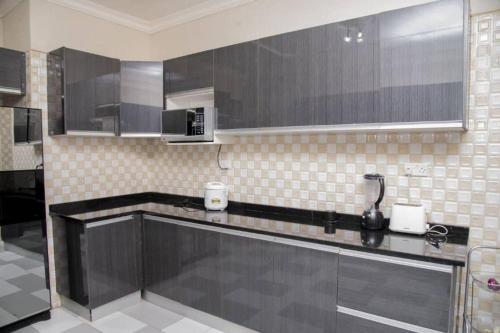 une cuisine avec des armoires noires et un comptoir dans l'établissement Royal Suites Apartments, à Lusaka