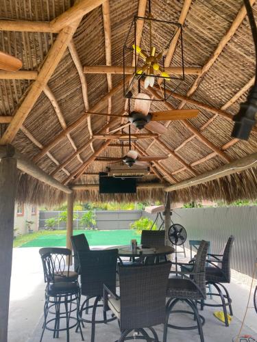 a patio with a table and chairs under a straw roof at Paradise Oasis1 in Miami