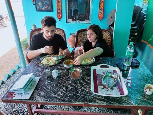 Ein Mann und eine Frau sitzen am Tisch und essen Essen. in der Unterkunft Veera's Hostel in Pushkar