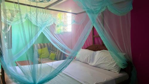 a bedroom with a canopy bed with mosquito nets at Armaan Guest House in Diani Beach