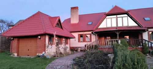 une maison avec un toit rouge et une allée en briques dans l'établissement Agroturystyka Pod Lipa, à Boreczno