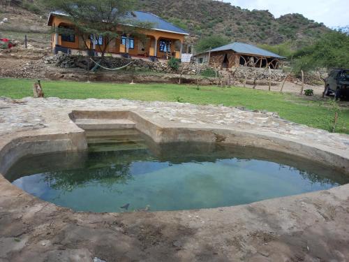 une grande piscine d'eau en face d'une maison dans l'établissement Lake Natron Maasai Guesthouse, à Mtowabaga