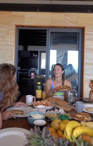 a group of people sitting around a table with food at Dodo House auberge de jeunesse in Saint-Leu