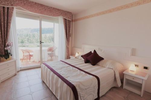 a bedroom with a bed and a large window at Hotel Miramonti in Bagno di Romagna