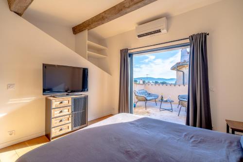 um quarto com uma cama, uma televisão e uma janela em Maison de Village pittoresque climatisée, terrasse em Plan-de-la-Tour