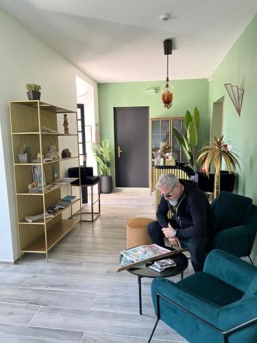 a man sitting on a couch in a living room at Hôtel Paradis in Bormes-les-Mimosas