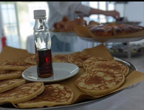 Una mesa con un plato de panqueques y una botella de jarabe. en Rodi Resort, en Rodi Garganico