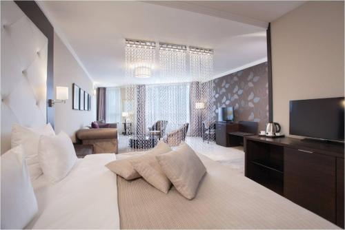 ベオグラードにあるホテル コンスタンティン ザ グレートのベッドルーム(大型ベッド1台付)、リビングルームが備わります。