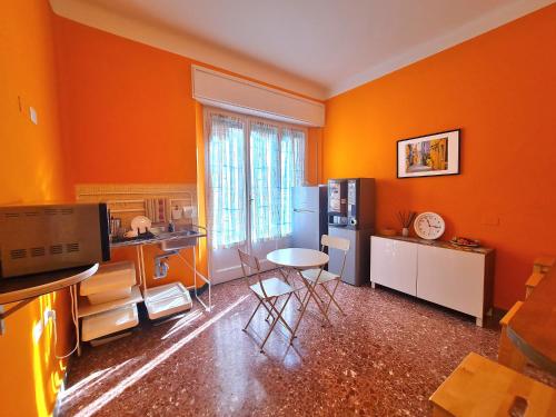 Una cocina con paredes naranjas y una mesa y un refrigerador. en LC ROOMS Pisa, en Pisa