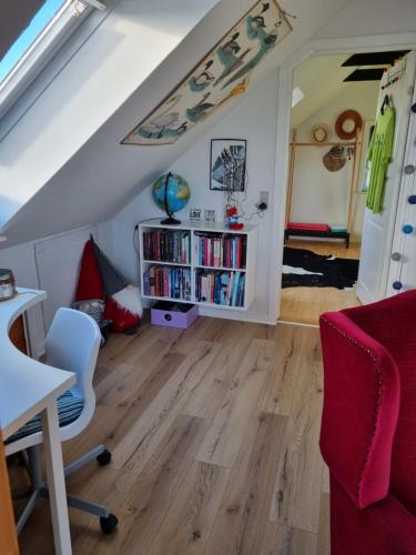 a living room with a red couch and a book shelf at Marsvinslund bed and breakfast in Viborg