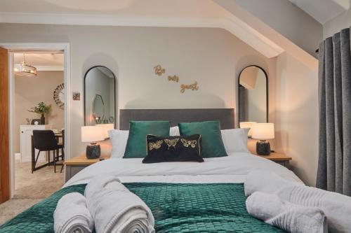 1 dormitorio con 1 cama grande con almohadas verdes en The Swan Apartment - Free parking en Harrogate