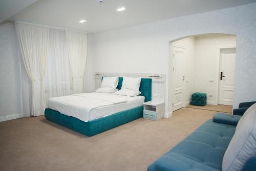 sypialnia z łóżkiem i niebieską kanapą w obiekcie Hotel VinoGrad w mieście Haysyn