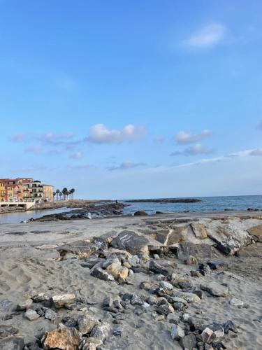 a beach with rocks and the ocean and buildings at Bistrot del mare in Santo Stefano al Mare