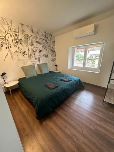 a bedroom with a large green bed and a window at La Maison du Moulin à Vent in La ForestiÃ¨re