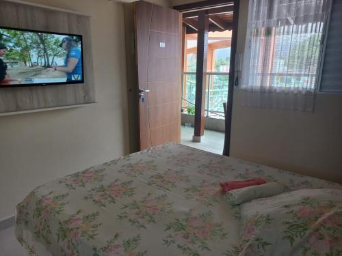 Schlafzimmer mit einem Bett und einem Flachbild-TV in der Unterkunft Kitnetes & Aptos Praia do Capricórnio in Caraguatatuba