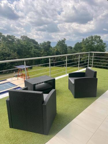a patio with two chairs and a table on the grass at La finca Luxury House in Anapoima
