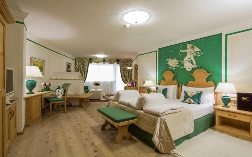 a bedroom with a large bed with a green wall at Hotel Sassongher in Corvara in Badia