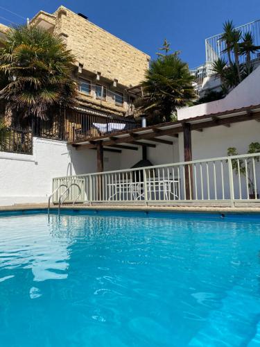 a swimming pool with blue water in front of a house at Departamento entero Reñaca - Jardín del mar in Viña del Mar