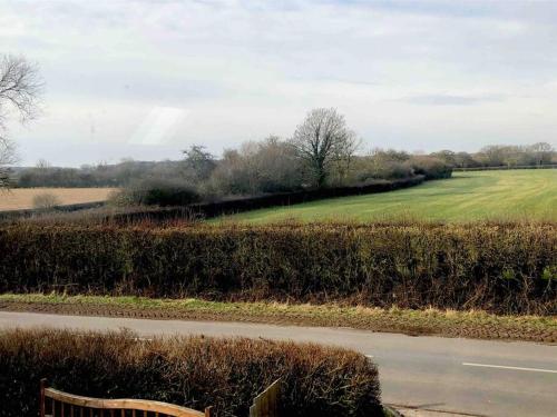 a view of a field and a road with a bench at Harrow Hayloft Rural 80m2 Village Hideaway Retreat in Himbleton