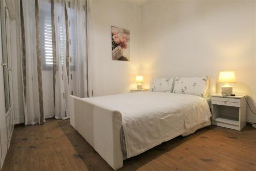 Un dormitorio blanco con una cama blanca y dos lámparas. en Sea Balcony Apartment Savudrija, en Savudrija