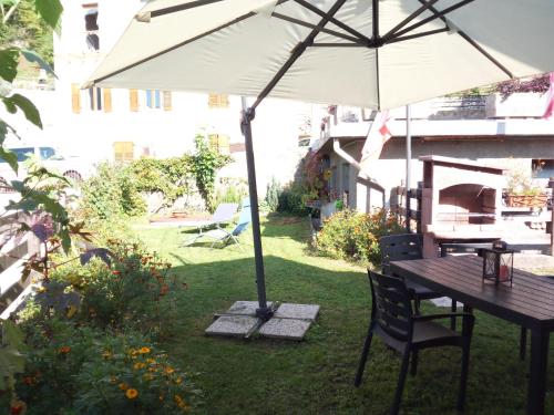 a table with an umbrella in a garden at casetta Vittorio in Mezzolago