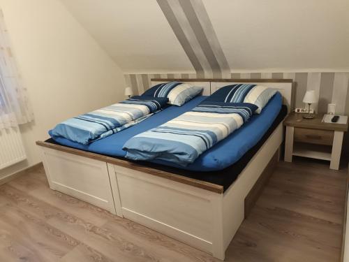 Una cama grande con almohadas azules y blancas. en Ferienwohnung Wiesengrund, en Hahnstätten