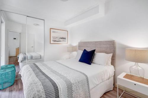 - une chambre blanche avec un grand lit et des oreillers bleus dans l'établissement Iluka Twelve at Iluka Resort Apartments, à Palm Beach
