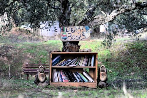a book shelf with a sign on it next to a bench at Albergue a Casina di Marcello in Palas de Rei 