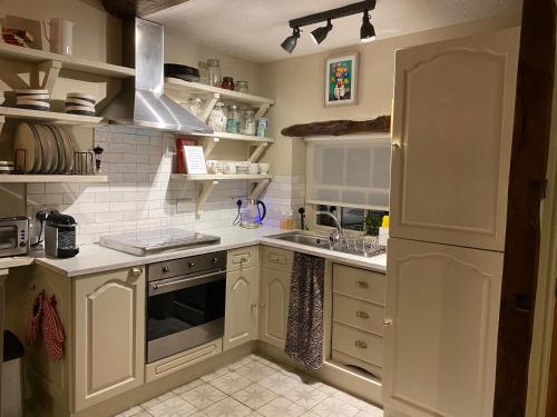 a kitchen with white cabinets and a sink at The Folly in Sedbergh