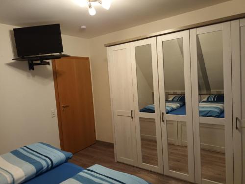 a bedroom with white cabinets and a tv and a bed at Ferienwohnung Wiesengrund in Hahnstätten