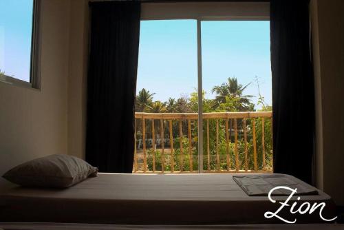 a bed with a window with a view of a balcony at Zion Beach House in Cartagena de Indias