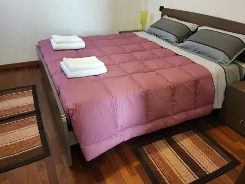 ein rosa Bett mit zwei Handtüchern darüber in der Unterkunft Residence Belvedere Apartment Bolvedro in Tremezzo