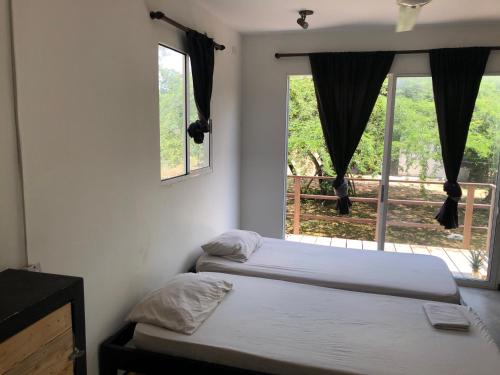 two beds in a room with two windows at Zion Beach House in Cartagena de Indias