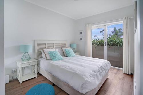 een witte slaapkamer met een bed en een groot raam bij Barrenjoey at Iluka Resort Apartments in Palm Beach